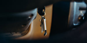 Titanium keychain bottle opener hanging from key ring in car