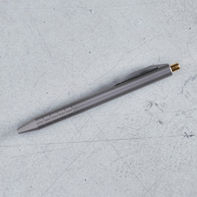 the retract titanium click pen on the ground of our california hanger showing off it's bronze clicker and titanium tumbled sheen #material_titanium-bronze