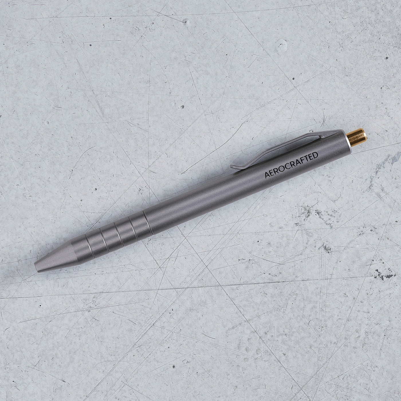 the retract titanium click pen on the ground of our california hanger showing off it's bronze clicker and titanium tumbled sheen #material_titanium-bronze