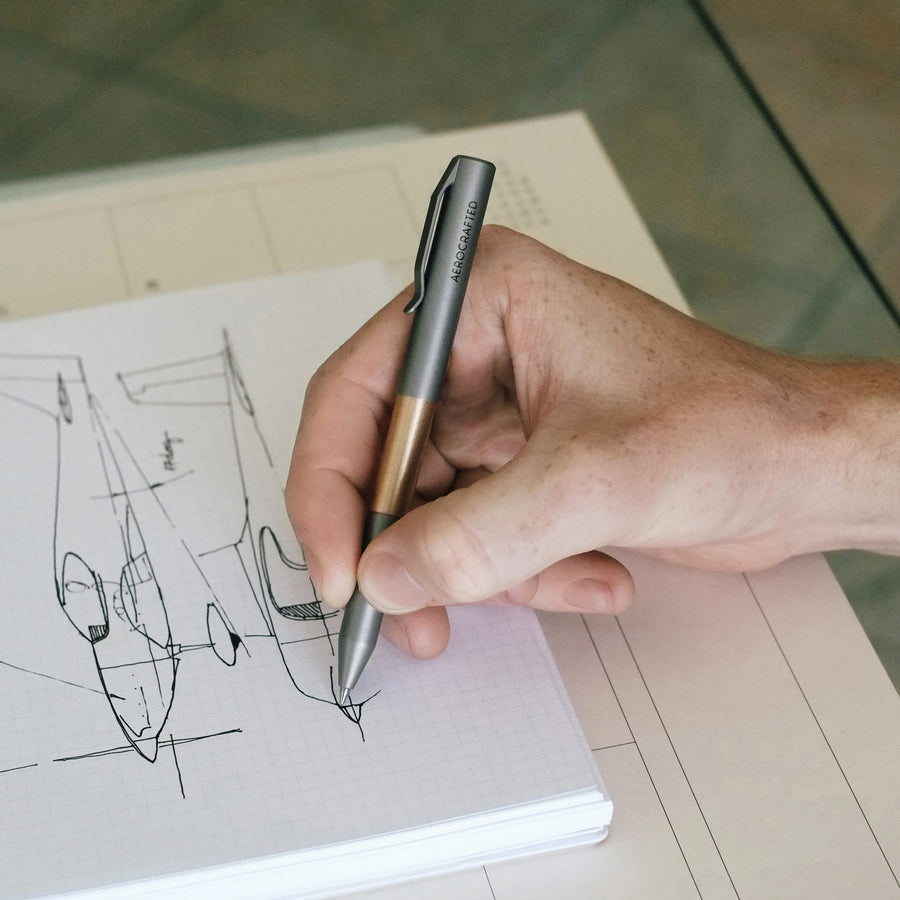 hand using titanium pen to draw airplane diagram #material_titanium-bronze