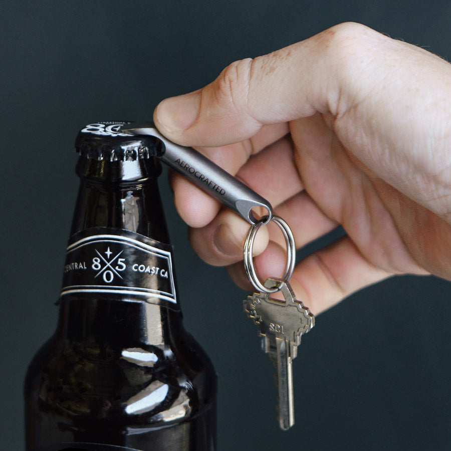 The wingman titanium bottle opener is an edc bottle opener made to fit on a key ring and assist in opening bottles and can be used as a tiny pry bar